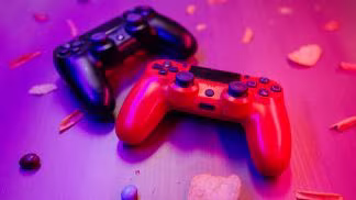 Two gaming controller black and red on pink background